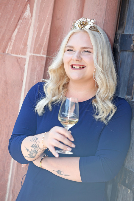 Annika Walther lehnt mit einem Glas Riesling an der Mauer.