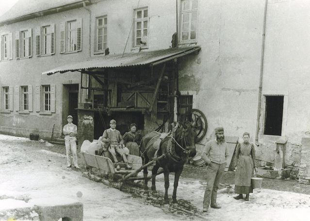 Im Winter wurde das Mehl per Schlitten transportiert. Im Vordergrund: Müller Peter Schamari (stehend, mit Bart) vor der Schamari-Mühle.